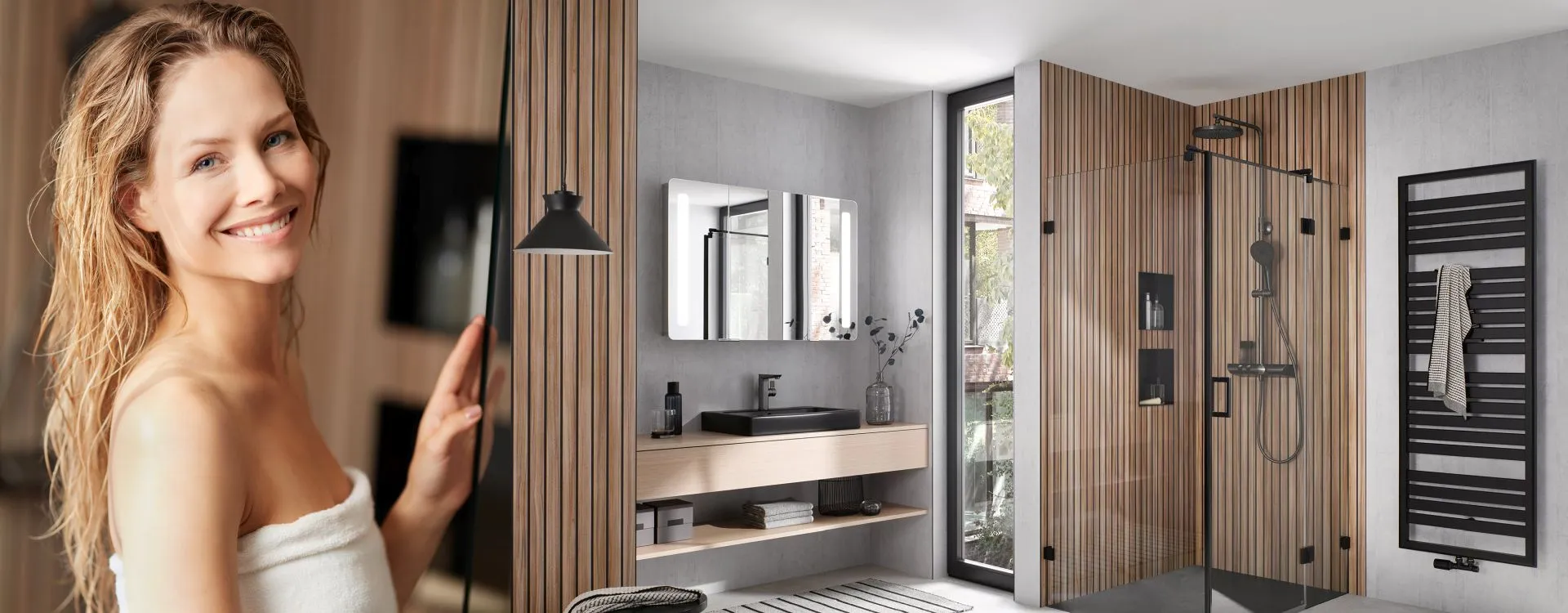Frau im Wellness-Badezimmer vor moderner Walk-in-Dusche, Holzlamellen, Doppelspiegel und hellem Tageslicht.