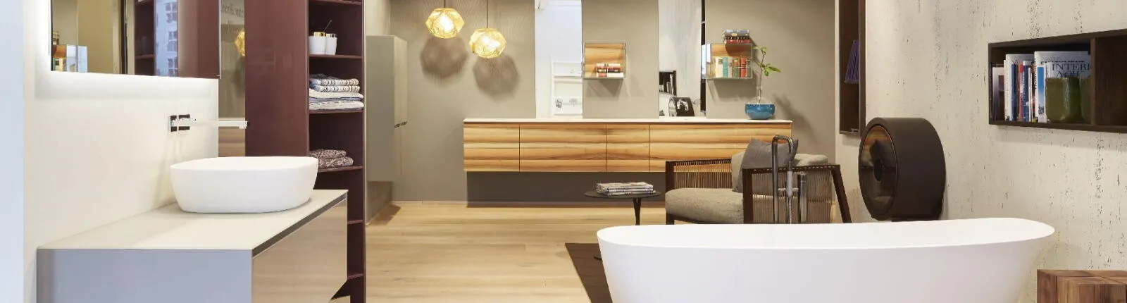 Modernes Badezimmer mit freistehender Badewanne, Aufsatzwaschbecken, Holzmöbeln und warm beleuchteter, wohnlicher Gestaltung.