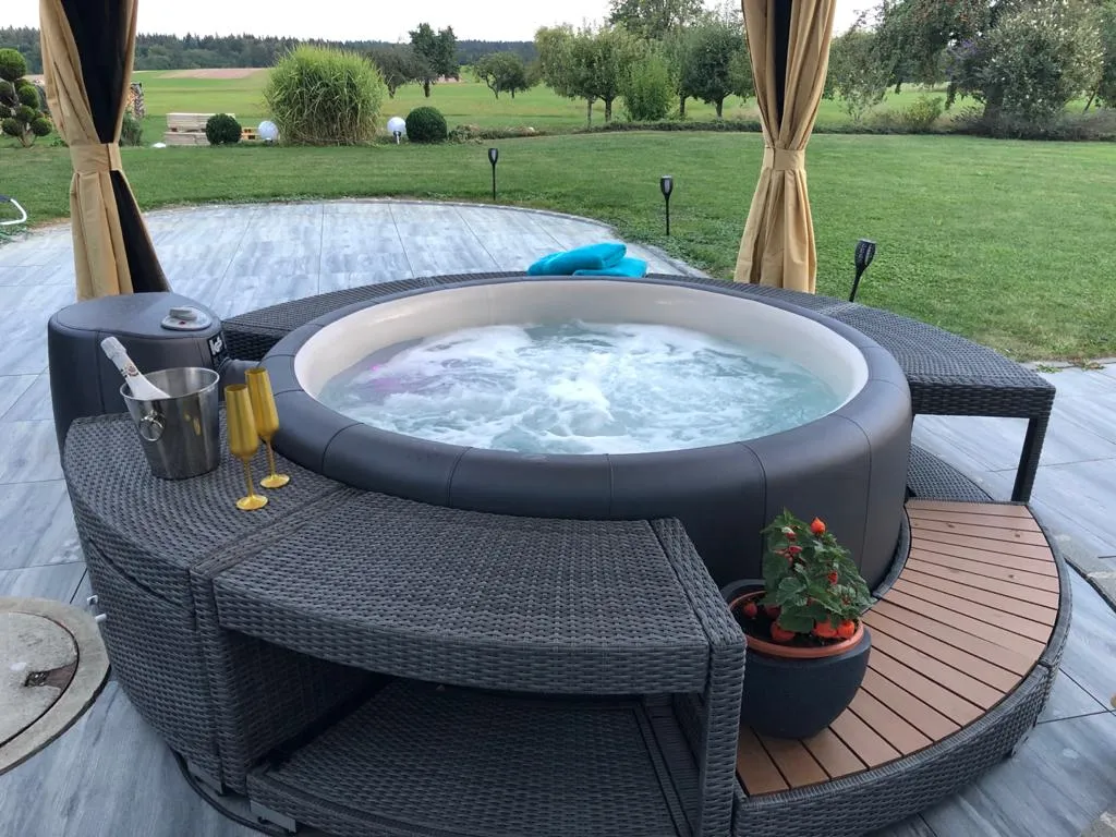 Whirlpool im Außenbereich auf Terrasse mit Sitzbank und Blick in den Garten für private Wellness.
