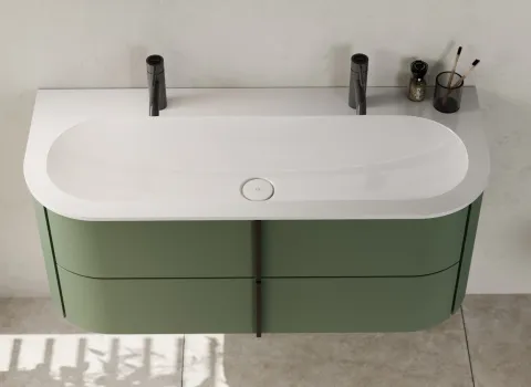 Nahaufnahme eines modernen Waschtisches mit einer eleganten, abgerundeten weißen Oberfläche und einem großen, eingelassenen Waschbecken.
