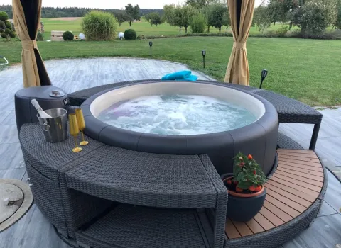 Whirlpool im Außenbereich auf Terrasse mit Sitzbank und Blick in den Garten für private Wellness.