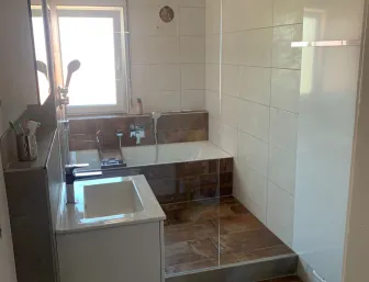 Altbau-Badezimmer nach der Sanierung mit moderner Dusche, Badewanne und neuen Fliesen.