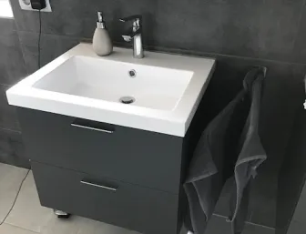 Modernes Gäste Badezimmer mit Waschtisch, grauen Fliesen und kompaktem Design.