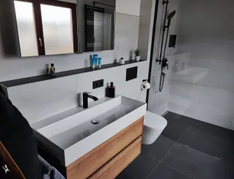 Modernes Badezimmer mit schwarzer Armatur, Holzwaschtisch und bodengleicher Dusche.