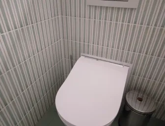 Hängendes WC mit weißer Keramik, grünen Bodenfliesen und schmal gestreifter Wandgestaltung sowie integriertem Spülknopf.